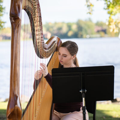 Hannah Warren Harpist - Professional Wedding and Event Harpist Ottawa Kingston Montreal - Hannah playing Salvi Scolpita harp at a wedding out by the water Chateau Montebello