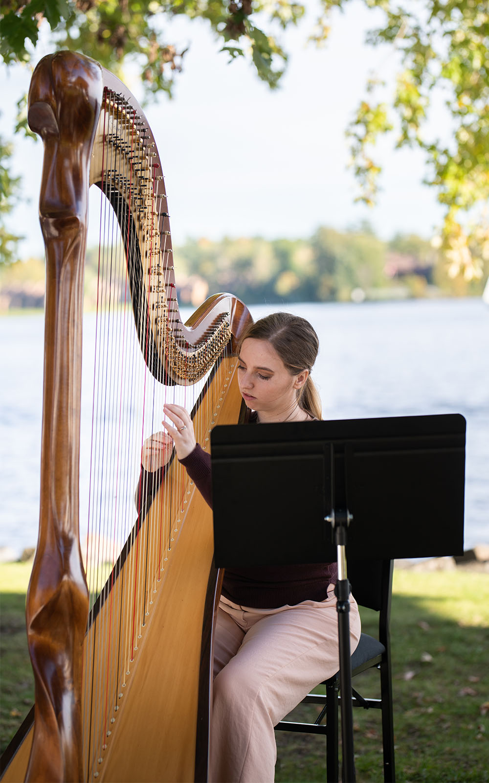 Hannah Warren Harpist - Professional Wedding and Event Harpist Ottawa Kingston Montreal - Hannah playing Salvi Scolpita harp at a wedding out by the water Chateau Montebello